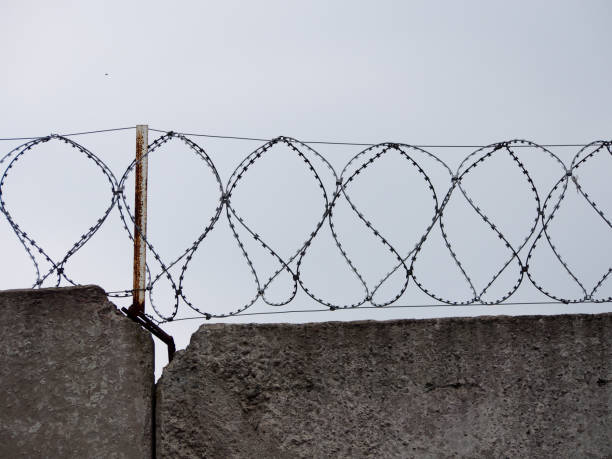 istock Concrete wall with coils of barbed wire. 1153844506