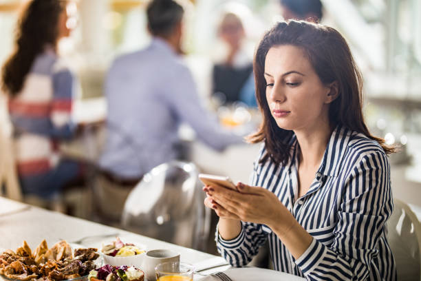 istock Young businesswoman using mobile phone on a lunch break in a restaurant. 1153846072