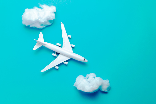 Jet airplane flying between the clouds, minimal concept, on blue background. Minimal transportation, travel or vacation concept