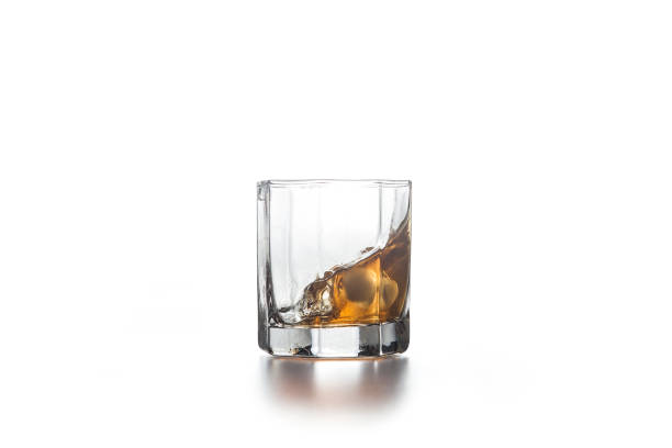istock Whiskey splash in glass with ice on light background. 1153849441