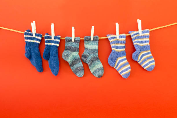 istock Colorful woolen socks on a rope on red background 1153849670