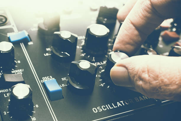 Musician adjusts knob on retro analog synthesizer for making electronic music