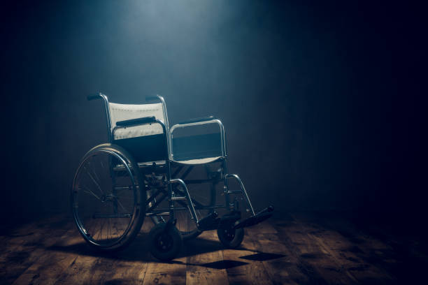 Lonely empty wheelchair in dark room. Medical equipment for disabled patient.
