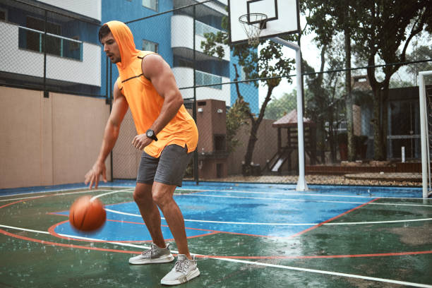 athletic young man playing basketball on a rainy day - basketball sport storm star imagens e fotografias de stock