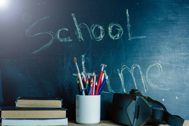 istock Concept back to school, virtual reality technology VR helmet. Pencils, books on the background of the school board 1153855320