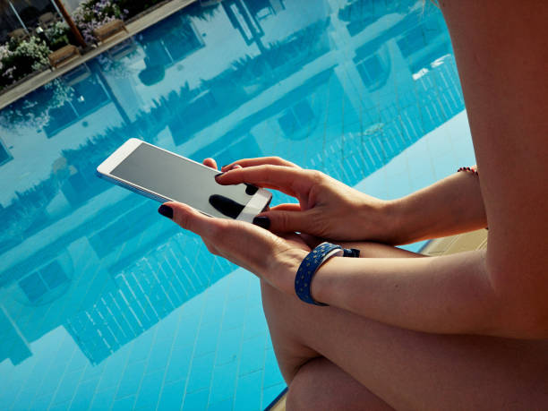 istock Young woman using cellphone near the swimming pool. 1153856389