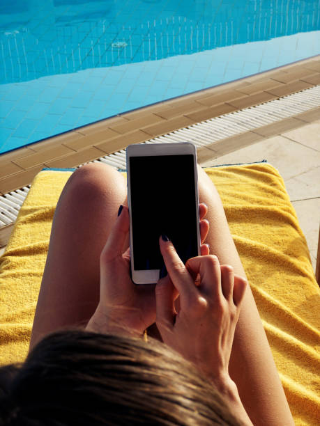 istock Young woman using cellphone near the swimming pool. 1153856475