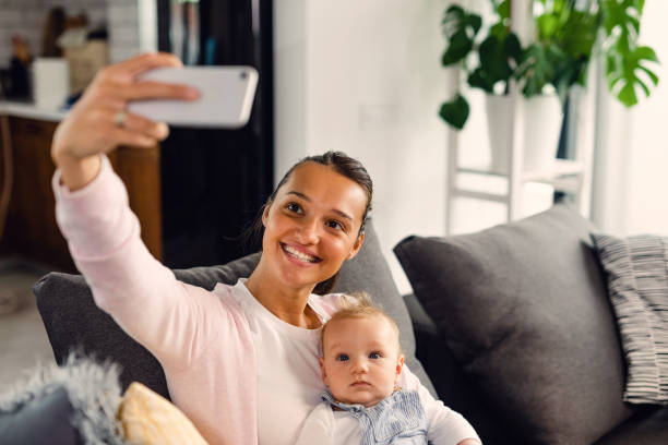istock Young mother having fun while taking selfie with her baby boy at home. 1153856761