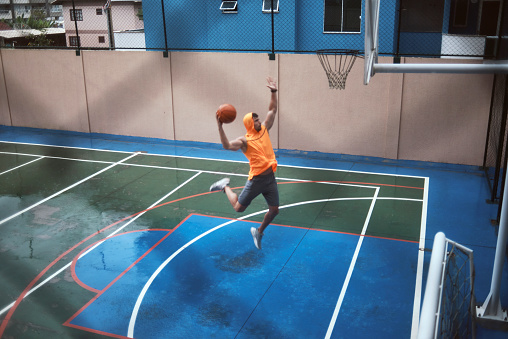 young man playing basketball on a rainy day