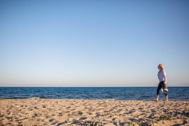 istock Woman watching sunset by the sea 1153860968