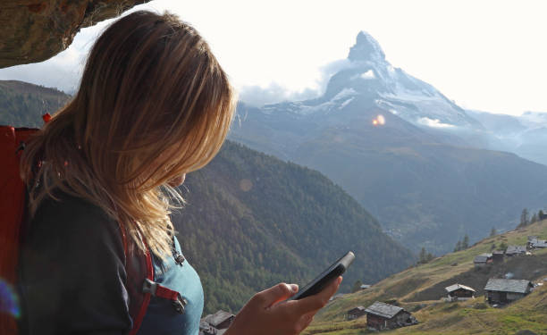 istock Young woman uses cell phone under chalet eaves 1153861009