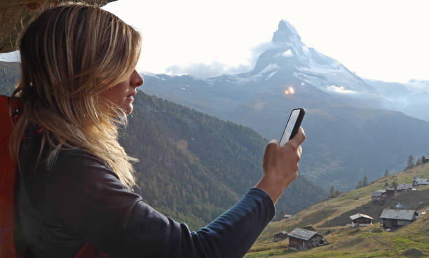 istock Young woman uses cell phone under chalet eaves 1153861036