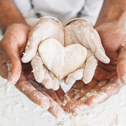 Afro man's hands holding childs hands with heart shaped pastry. Love and family concept