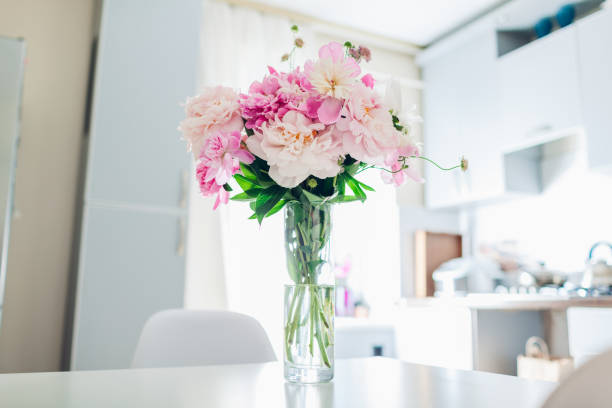 istock Pink peonies. Modern kitchen design. Interior of white and silver kitchen decorated with flowers. 1153861314