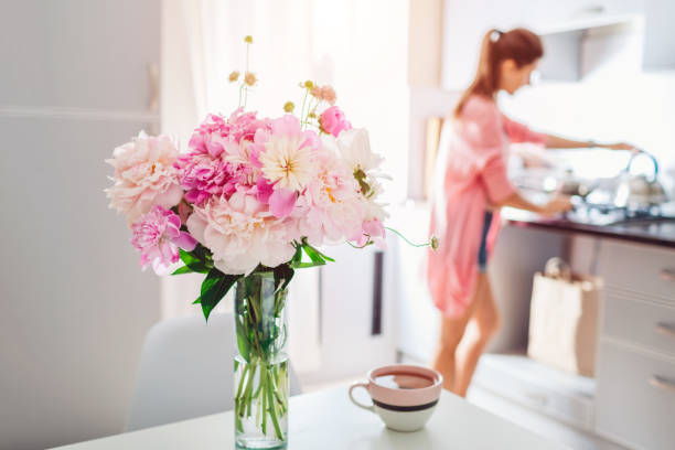 istock Modern kitchen decorated with pink peonies. Housewife cooking dinner. Interior design. 1153861332