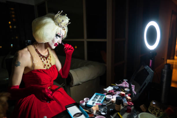 istock Bizarre man with make-up in red dress with long nails 1153862731