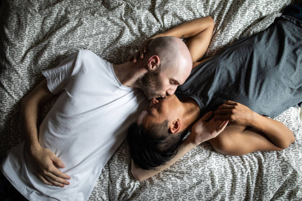 homosexuelles paar küsst im bett - auf den mund küssen stock-fotos und bilder