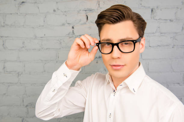 istock Attractive young man in white shirt touching his glasses 1153865491