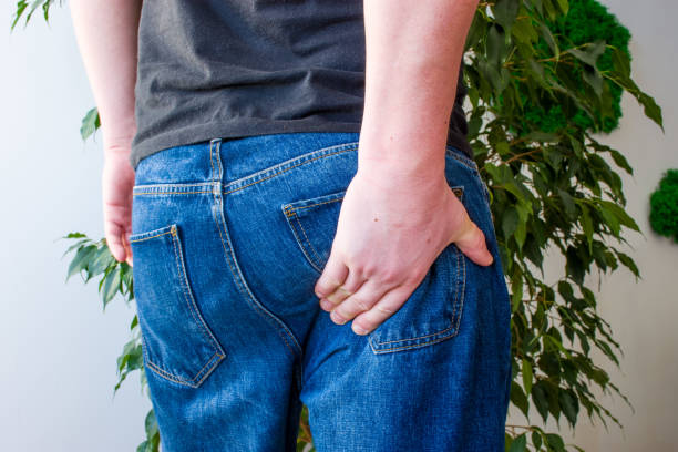 남자는 엉덩이의 아래 부분에 손을 유지 합니다. 좌 골 신경의 출구에 통증의 개념 사진 증상, 염증, 신경 통 또는 척추, 통증 근육, 직장 이나 항문에 고통 - 엉덩이 뉴스 사진 이미지