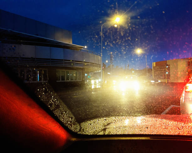 istock Night driving: dazzling lights seen through car windscreen on a rainy road 1153868223