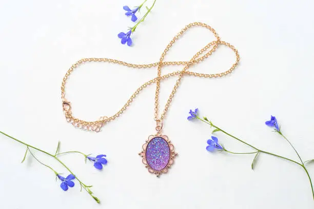 Photo of Beautiful female pendant on a chain, decoration for girls on white background, purple stone in gold frame