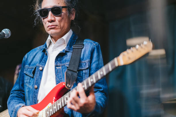 istock Male musician with dreadlocks playing guitar and singing on stage 1153869997