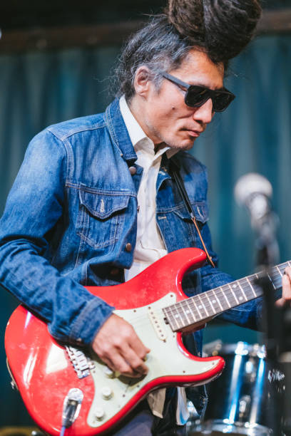 istock Male musician with dreadlocks playing guitar and singing on stage 1153870069