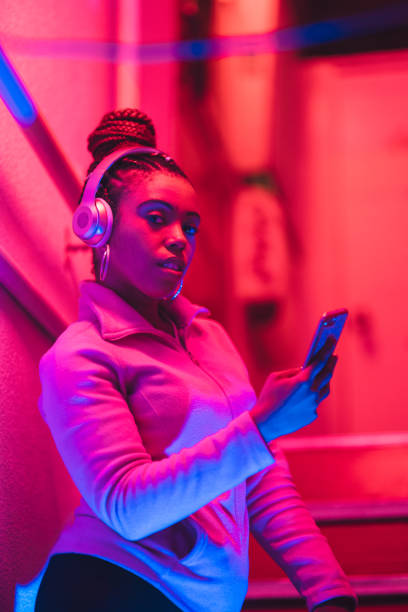 portrait of young black woman listening to music under neon lights - red hair hairstyle dyed hair women imagens e fotografias de stock