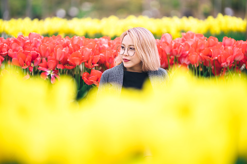 Portrait of young beautiful millennial generation woman in tulip field.