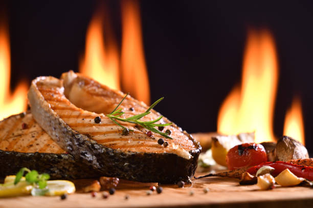 istock Grilled salmon fish and various vegetables on wooden table background 1153873798