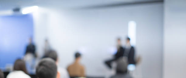 istock Blurred seminar panel speakers at corporate conference giving speech.  Presenters giving lecture to business audience. Defocused managers leading discussion in hall during company training event. 1153875302