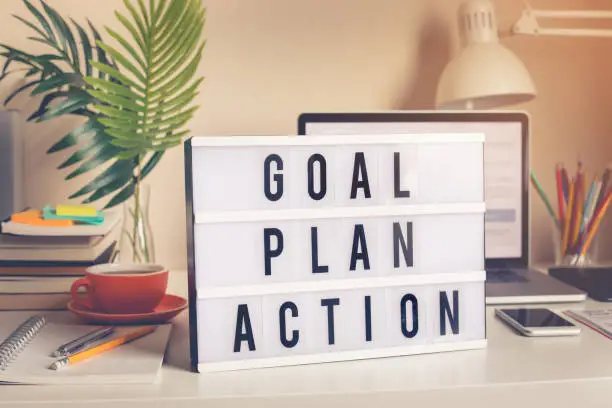 Photo of Goal,plan,action text on light box on desk table in home office