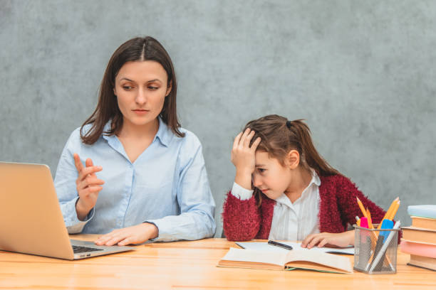 istock Mom and daughter on a gray background. During this, Mom found a solution to the problem on the laptop, showing her daughter. The girl is amazed and puts her hand on her head. 1153881978