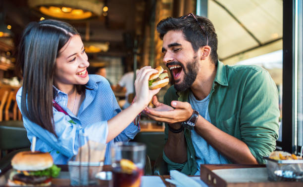 カフェに座って朝食を食べている若いカップル。愛、デート、食べ物、ライフスタイルコンセプト - young male ストックフォトと画像