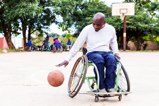 un giocatore di basket in carrozzina che dribbla la palla da basket a terra - basket su sedia a rotelle foto e immagini stock