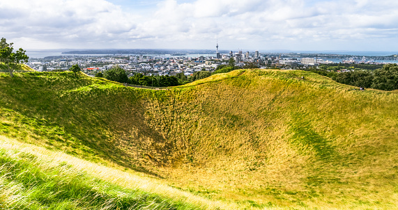 A wide angle panorama of the volcanic crater of Mount Eden (or Maungawhau), with Auckland's city skyline on the horizon.