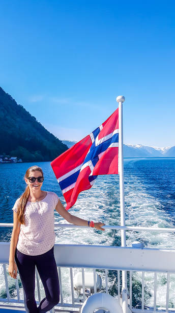 norvège-une jeune fille prenant le tour aboat sur le fjord. ondulant le drapeau norvégien derrière lui - flam aurlandsfjord sognefjord fjord photos et images de collection