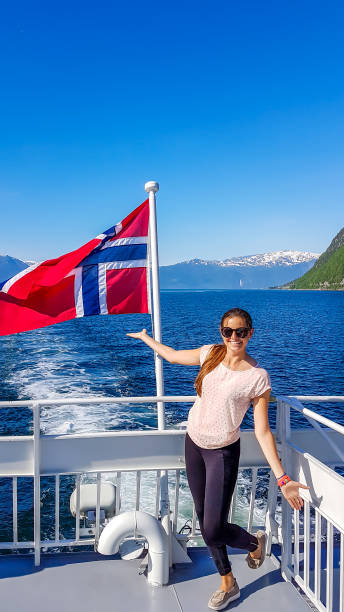 norvège-une jeune fille prenant le tour aboat sur le fjord. ondulant le drapeau norvégien derrière lui - flam aurlandsfjord sognefjord fjord photos et images de collection