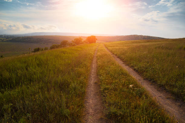 istock red sunset over green field with road 1153889840