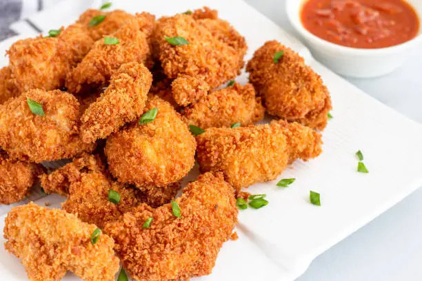 Chicken Nuggets on a Plate Served with Red Sauce on White Background. Popular American Fried Food, Snack, Fast Food, Fried Chicken Dish."n