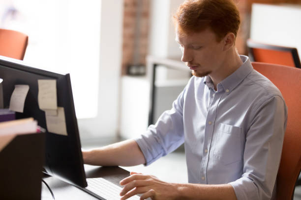 istock Focused redhead male employee working on pc in office 1153894559