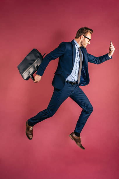 istock Man with mobile phone jumping with briefcase 1153895265