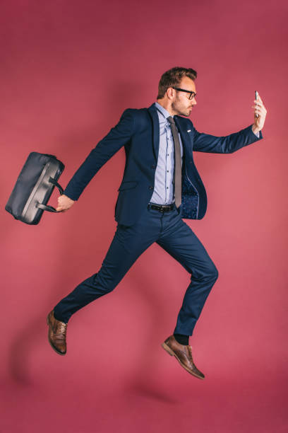 istock Man with mobile phone jumping with briefcase 1153895279