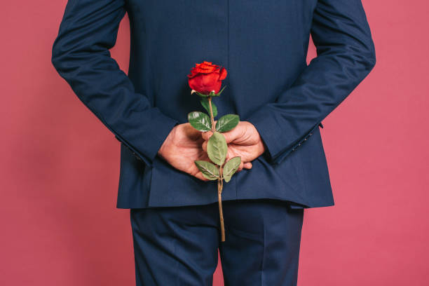 Man holding a rose Unrecognizable charming well dressed man holding a red rose rose man stock pictures, royalty-free photos & images