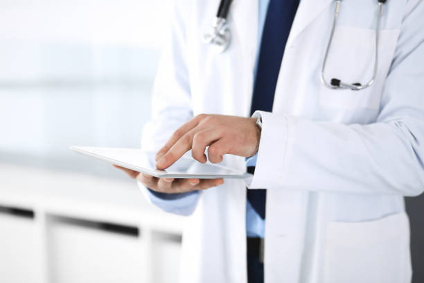 istock Doctor man using tablet computer for network research or virtual disease treatment, hands close-up. Perfect medical service in clinic. Modern  medicine, medic data and healthcare concepts 1153897116