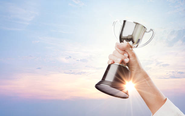 la mano de la mujer que levantó el trofeo o la cabeza con un fondo de cielo, transmitir la sensación de victoria alcanzada, o fondo de banner panorámico con el espacio de copia - arms lifted fotografías e imágenes de stock