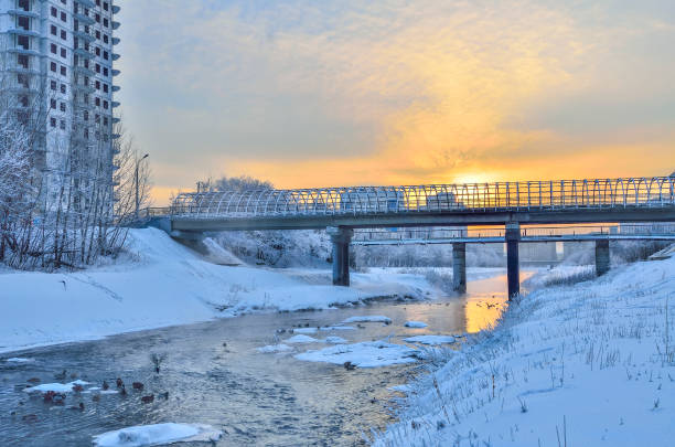 istock Winter cityscape with ducks in little warm river at sunset 1153899887