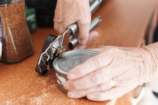 Senior woman's hands opening a can with a can opener