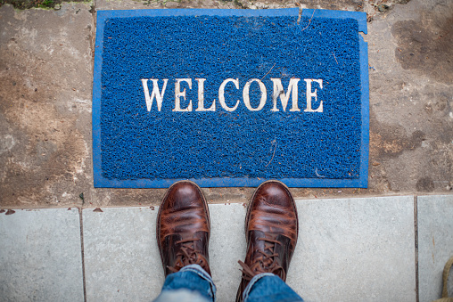 Person with boots standing in front of welcome mat