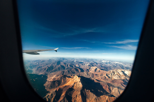Aerial view of the Andes mountain range through the window of an airplane, on the border between Chile and Argentina